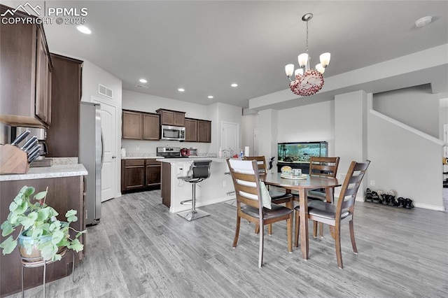 dining room with a chandelier, light wood-type flooring, recessed lighting, and baseboards