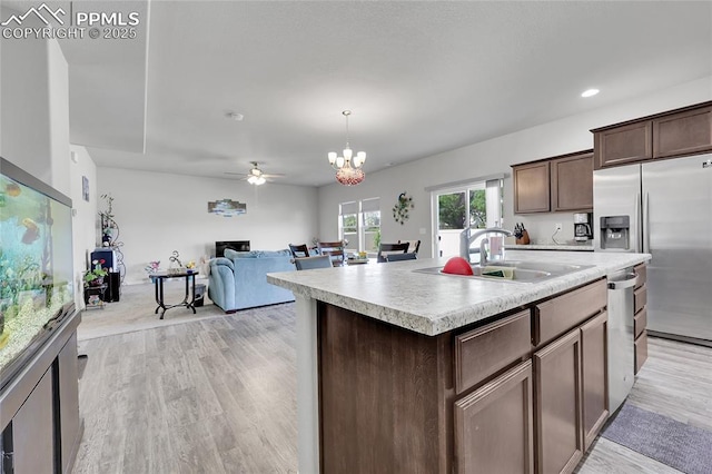 kitchen with a sink, stainless steel appliances, light countertops, dark brown cabinetry, and a ceiling fan