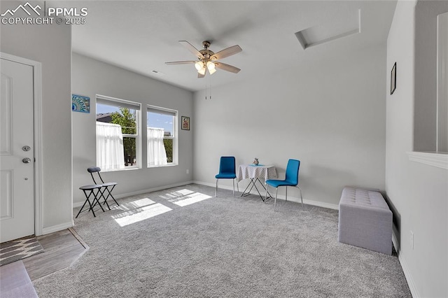 sitting room featuring attic access, carpet flooring, ceiling fan, and baseboards