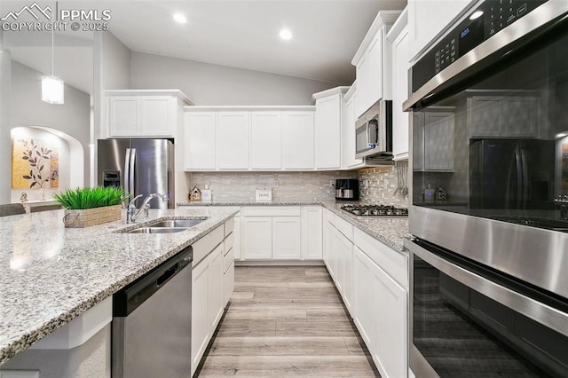 5799 Adkisson Pl, Colorado Springs, CO 80924 - kitchen with stainless steel appliances, a sink, white cabinetry, decorative backsplash, and light wood-type flooring