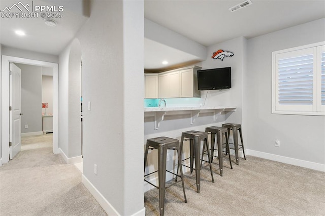 5799 Adkisson Pl, Colorado Springs, CO 80924 - kitchen featuring light carpet, a breakfast bar area, baseboards, light countertops, and white cabinetry