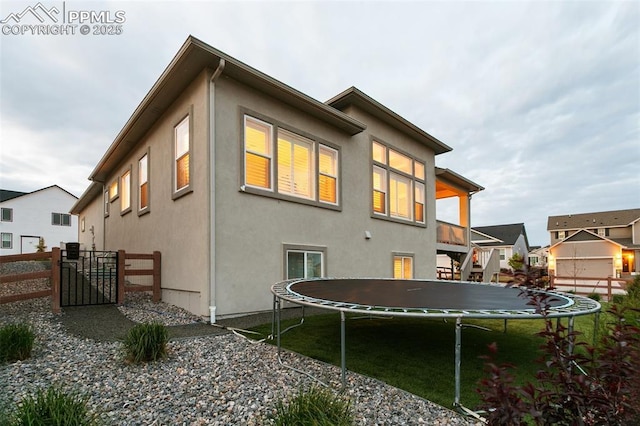 5799 Adkisson Pl, Colorado Springs, CO 80924 - rear view of property with a trampoline, stucco siding, and stairway
