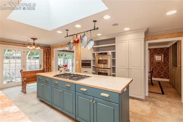 24 Upland Rd, Colorado Springs, CO 80906 - kitchen with ornamental molding, appliances with stainless steel finishes, wallpapered walls, a skylight, and a kitchen island