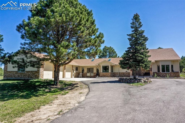 390 E Stirrup Trl, Monument, CO 80132 - ranch-style home featuring asphalt driveway, a garage, a front yard, and brick siding