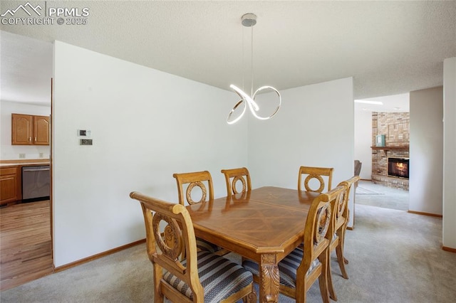 390 E Stirrup Trl, Monument, CO 80132 - dining room featuring light colored carpet, baseboards, a chandelier, and a fireplace