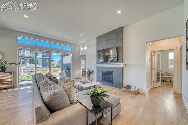 9473 Bugaboo Dr, Colorado Springs, CO 80924 - living area featuring light wood-type flooring, a tiled fireplace, baseboards, and recessed lighting