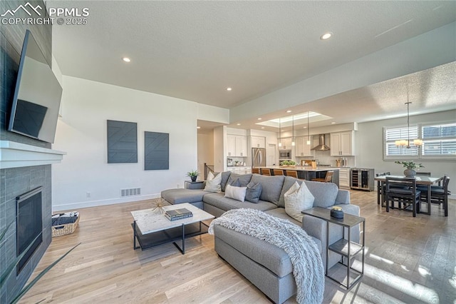 9473 Bugaboo Dr, Colorado Springs, CO 80924 - living room featuring light wood-style floors, a chandelier, a tile fireplace, baseboards, and recessed lighting