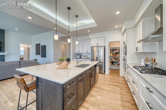 9473 Bugaboo Dr, Colorado Springs, CO 80924 - kitchen with appliances with stainless steel finishes, wall chimney range hood, a breakfast bar area, light wood-style floors, and recessed lighting
