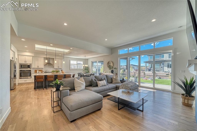 9473 Bugaboo Dr, Colorado Springs, CO 80924 - living area with light wood-type flooring, recessed lighting, a tray ceiling, baseboards, and a textured ceiling