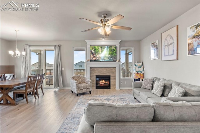 12879 Morning Creek Ln, Peyton, CO 80831 - living area featuring light wood-type flooring, a chandelier, a fireplace, ceiling fan, and baseboards