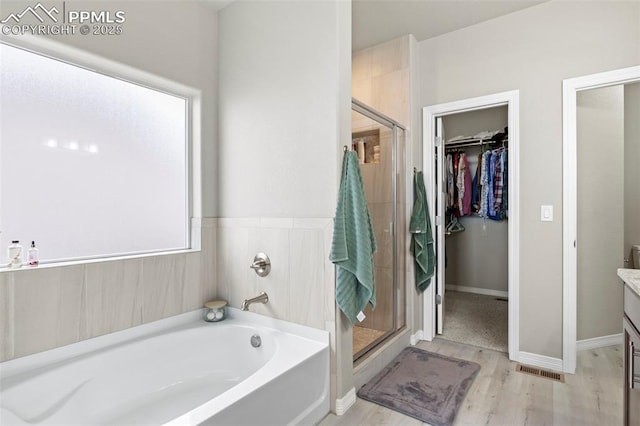 12879 Morning Creek Ln, Peyton, CO 80831 - full bath with wood finished floors, vanity, a garden tub, a stall shower, and a walk in closet