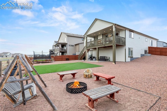 12879 Morning Creek Ln, Peyton, CO 80831 - back of property featuring a fire pit, a trampoline, and stairs