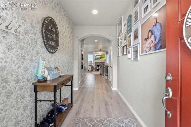 12879 Morning Creek Ln, Peyton, CO 80831 - hallway with arched walkways, wallpapered walls, light wood finished floors, and baseboards
