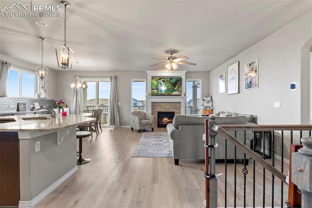 12879 Morning Creek Ln, Peyton, CO 80831 - living room with healthy amount of natural light, a stone fireplace, a ceiling fan, and light wood finished floors