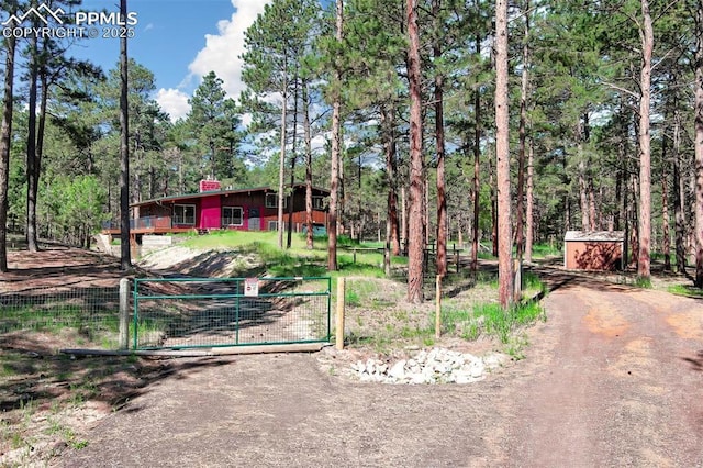 17990 Canterbury Dr, Monument, CO 80132 - view of front of home featuring a gate, a chimney, an outbuilding, and a wooded view