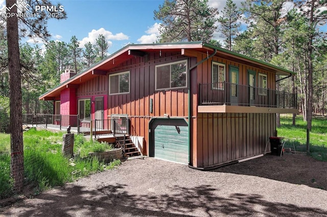 17990 Canterbury Dr, Monument, CO 80132 - rustic home with an attached garage, a chimney, board and batten siding, and dirt driveway