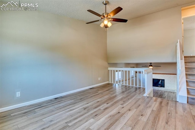 4472 Eastcrest Cir, Colorado Springs, CO 80916 - unfurnished living room with a ceiling fan, wood finished floors, a textured ceiling, baseboards, and a towering ceiling