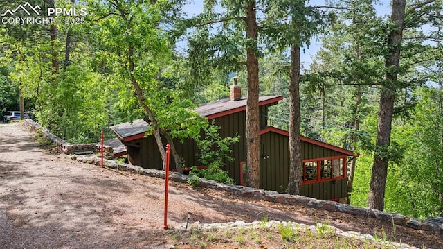 3875 Overlook Rd, Colorado Springs, CO 80906 - view of home's exterior featuring a chimney, board and batten siding, and a view of trees