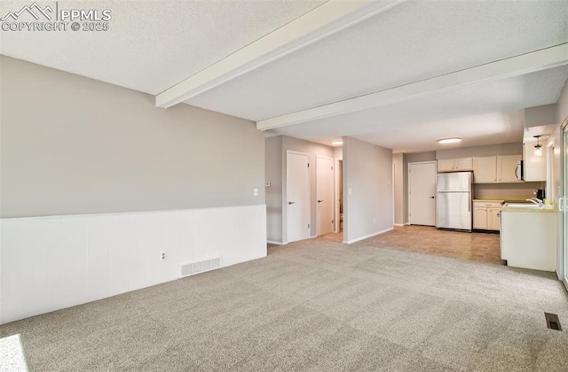 3177 Blue Mountain Way, Colorado Springs, CO 80906 - unfurnished living room featuring light carpet, beam ceiling, a wainscoted wall, and a sink