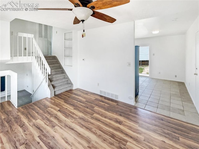 8193 Horizon Dr, Colorado Springs, CO 80920 - unfurnished living room featuring wood finished floors, ceiling fan, built in shelves, and stairway
