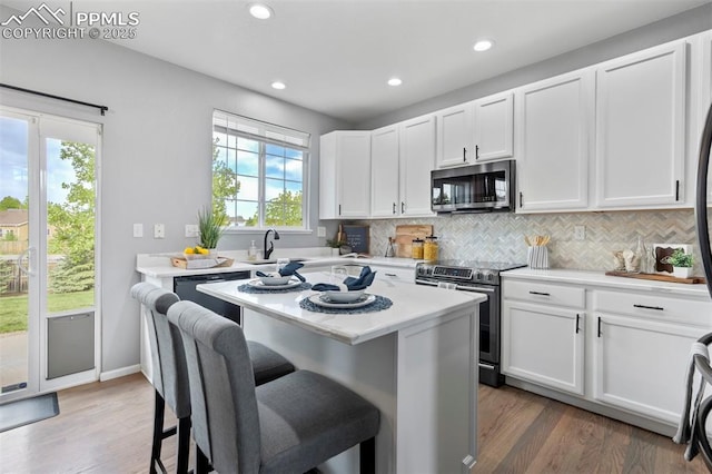 14213 Woodrock Path, Colorado Springs, CO 80921 - kitchen with appliances with stainless steel finishes, a kitchen bar, a sink, backsplash, and white cabinets