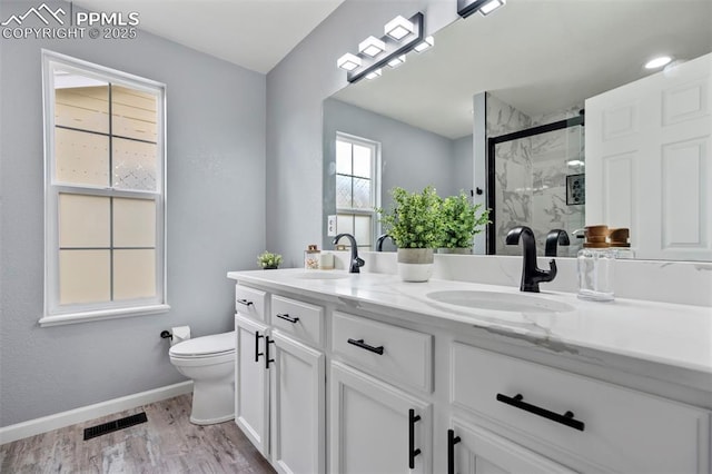 14213 Woodrock Path, Colorado Springs, CO 80921 - bathroom with double vanity, toilet, a marble finish shower, wood finished floors, and baseboards