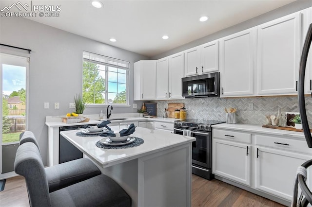 14213 Woodrock Path, Colorado Springs, CO 80921 - kitchen with stainless steel appliances, a sink, backsplash, wood finished floors, and white cabinets