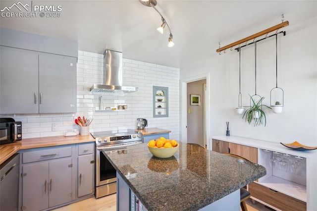 2430 N Tejon St, Colorado Springs, CO 80907 - kitchen featuring wall chimney range hood, appliances with stainless steel finishes, tasteful backsplash, and a kitchen island