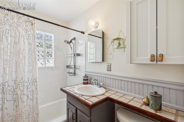 2430 N Tejon St, Colorado Springs, CO 80907 - full bathroom with shower / bath combo with shower curtain, vanity, a wainscoted wall, and toilet