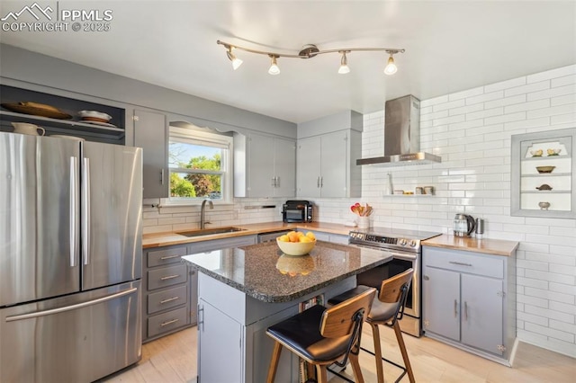 2430 N Tejon St, Colorado Springs, CO 80907 - kitchen featuring appliances with stainless steel finishes, wall chimney exhaust hood, a sink, gray cabinetry, and a breakfast bar