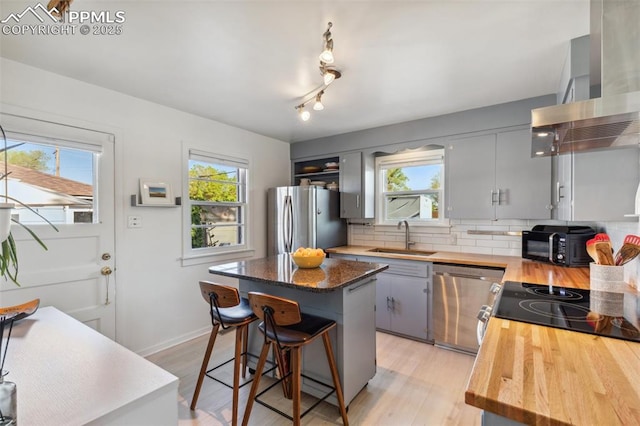 2430 N Tejon St, Colorado Springs, CO 80907 - kitchen featuring appliances with stainless steel finishes, wall chimney exhaust hood, a sink, a center island, and decorative backsplash
