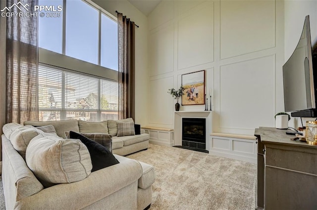 10368 Mount Evans Dr, Peyton, CO 80831 - living area featuring a decorative wall, a high ceiling, a fireplace with flush hearth, and carpet flooring