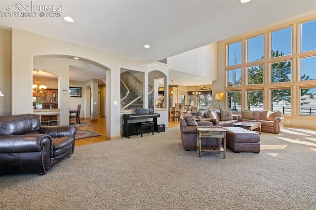 18320 Table Rock Rd, Colorado Springs, CO 80908 - carpeted living room with arched walkways, recessed lighting, a chandelier, and stairs