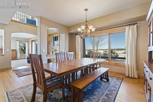 18320 Table Rock Rd, Colorado Springs, CO 80908 - dining space featuring arched walkways, a chandelier, light wood-type flooring, and baseboards