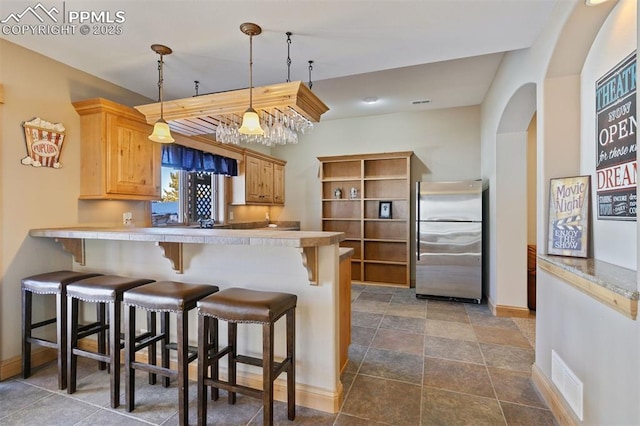 18320 Table Rock Rd, Colorado Springs, CO 80908 - kitchen with freestanding refrigerator, a peninsula, a breakfast bar, and baseboards