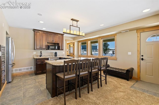 18320 Table Rock Rd, Colorado Springs, CO 80908 - kitchen featuring freestanding refrigerator, black microwave, a breakfast bar, light stone countertops, and a kitchen island