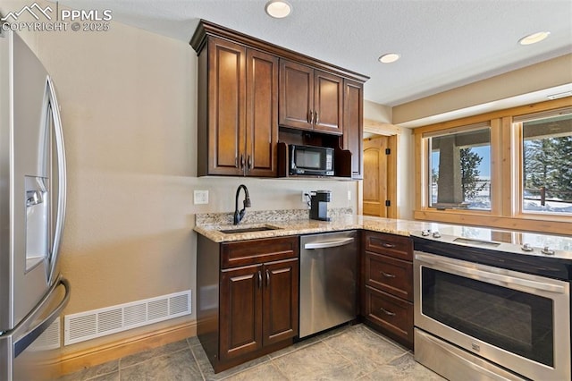 18320 Table Rock Rd, Colorado Springs, CO 80908 - kitchen with appliances with stainless steel finishes, a sink, light stone counters, baseboards, and recessed lighting
