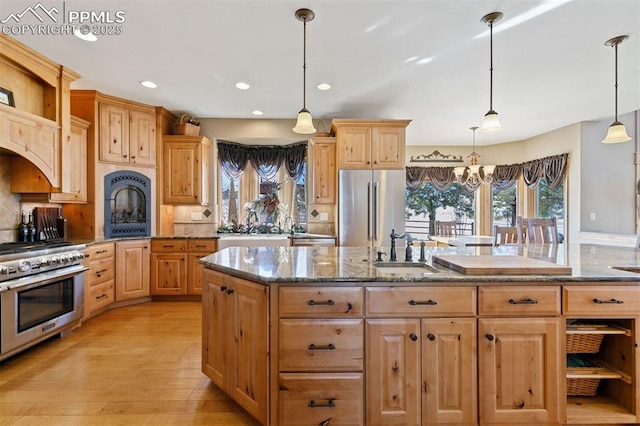 18320 Table Rock Rd, Colorado Springs, CO 80908 - kitchen featuring appliances with stainless steel finishes, a chandelier, a sink, a center island with sink, and light wood-type flooring