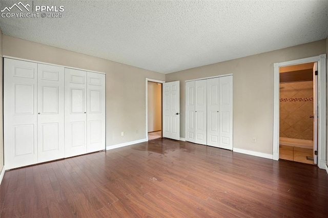 945 Bromefield Dr, Fountain, CO 80817 - unfurnished bedroom featuring two closets, wood finished floors, baseboards, a textured ceiling, and connected bathroom