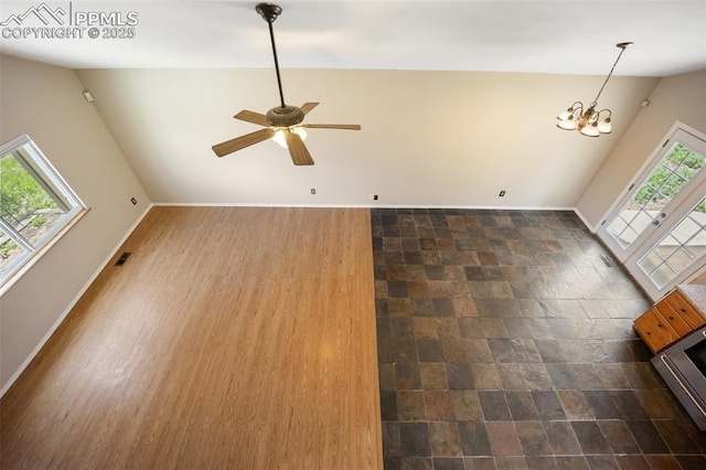 945 Bromefield Dr, Fountain, CO 80817 - unfurnished living room with a chandelier, ceiling fan, baseboards, vaulted ceiling, and dark stone finish flooring