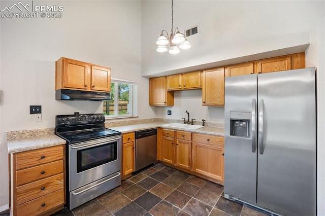 945 Bromefield Dr, Fountain, CO 80817 - kitchen with appliances with stainless steel finishes, a sink, under cabinet range hood, a towering ceiling, and a chandelier