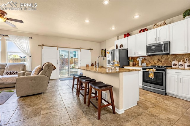 8004 Brittinger Way, Colorado Springs, CO 80951 - kitchen with appliances with stainless steel finishes, a sink, a barn door, open floor plan, and a kitchen bar