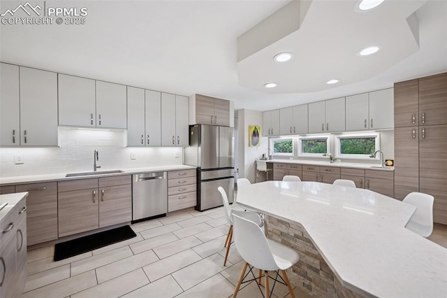 3 Heather Cir, Colorado Springs, CO 80906 - kitchen featuring appliances with stainless steel finishes, a sink, a breakfast bar area, light countertops, and decorative backsplash