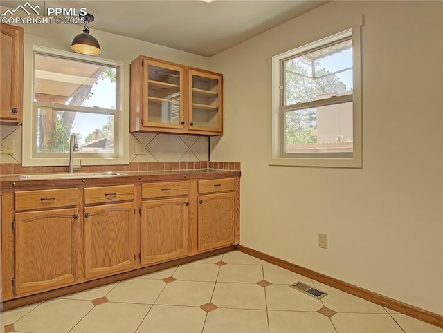 20 Swope Ave, Colorado Springs, CO 80909 - kitchen featuring a sink, glass insert cabinets, brown cabinetry, and baseboards