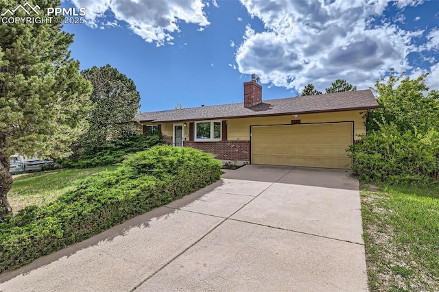 3286 Inspiration Dr, Colorado Springs, CO 80917 - single story home with an attached garage, brick siding, a chimney, and concrete driveway