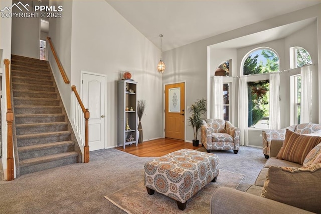 6557 Many Moon Dr, Colorado Springs, CO 80923 - living area featuring high vaulted ceiling, carpet, stairs, and baseboards