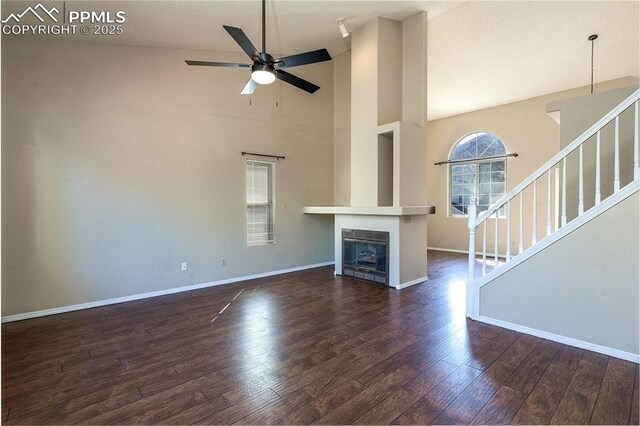 7435 Julynn Rd, Colorado Springs, CO 80919 - unfurnished living room featuring a ceiling fan, dark wood-style floors, stairs, baseboards, and high vaulted ceiling