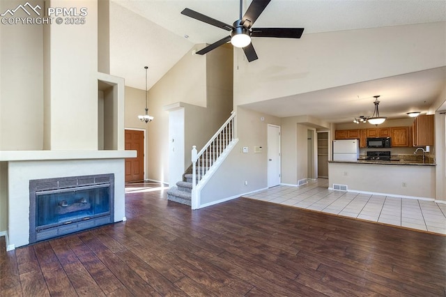 7435 Julynn Rd, Colorado Springs, CO 80919 - unfurnished living room with wood finished floors, a sink, high vaulted ceiling, ceiling fan, and stairs
