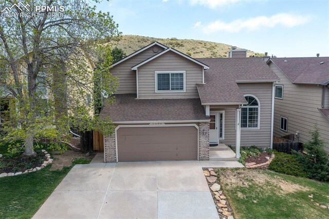 7435 Julynn Rd, Colorado Springs, CO 80919 - view of front of house featuring roof with shingles, an attached garage, concrete driveway, brick siding, and a chimney