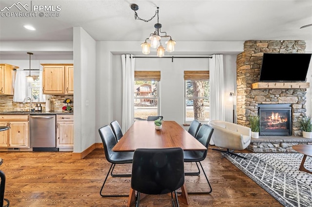 404 S Willow St, Woodland Park, CO 80863 - dining area with dark wood-style flooring, a stone fireplace, a chandelier, and baseboards